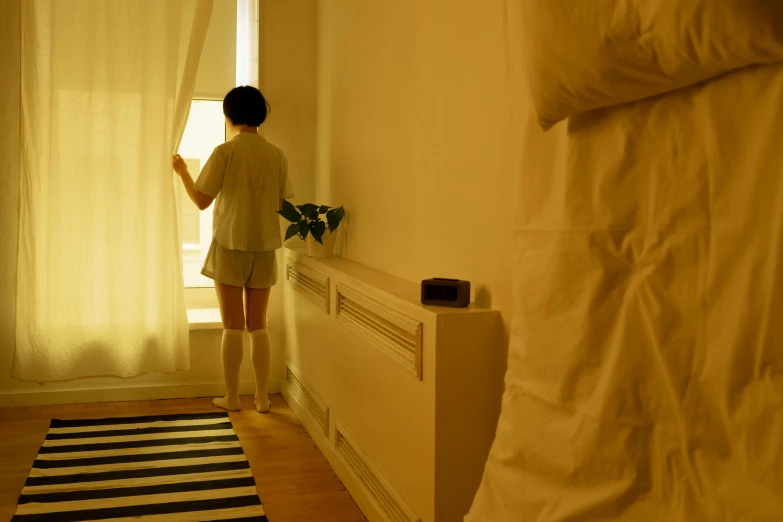 there is a woman standing by a bed and window