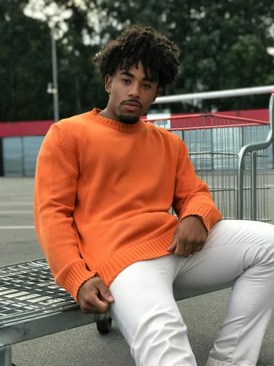 a man in an orange sweater sitting on a bench, inspired by Terrell James, pexels contest winner, happening, wearing off - white style, stood outside a corner shop, promo image, ashteroth