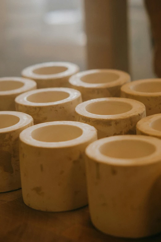 a group of cups sitting on top of a wooden table, a marble sculpture, inspired by Rachel Whiteread, unsplash, process art, large pipes, ivory, upclose, woodfired