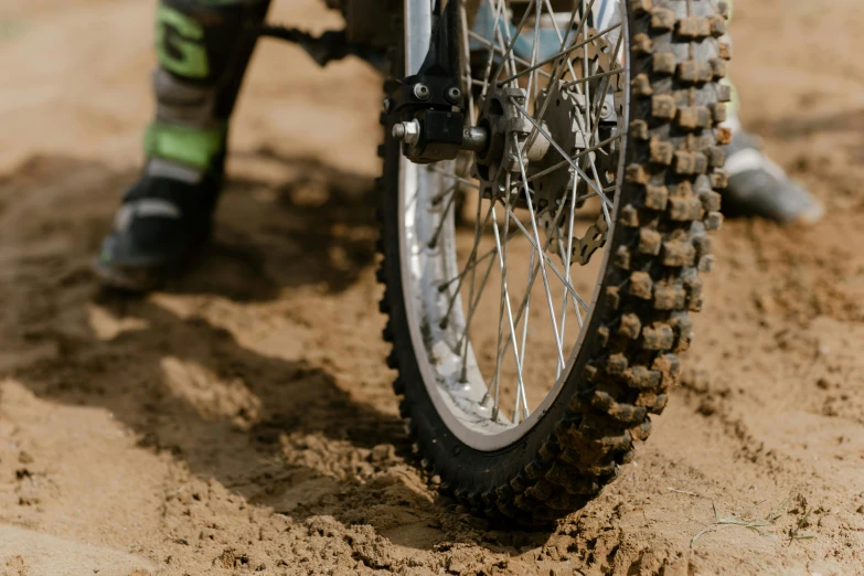 a person riding a dirt bike on a dirt road, a close up shot, cogs and wheels, avatar image, close up image
