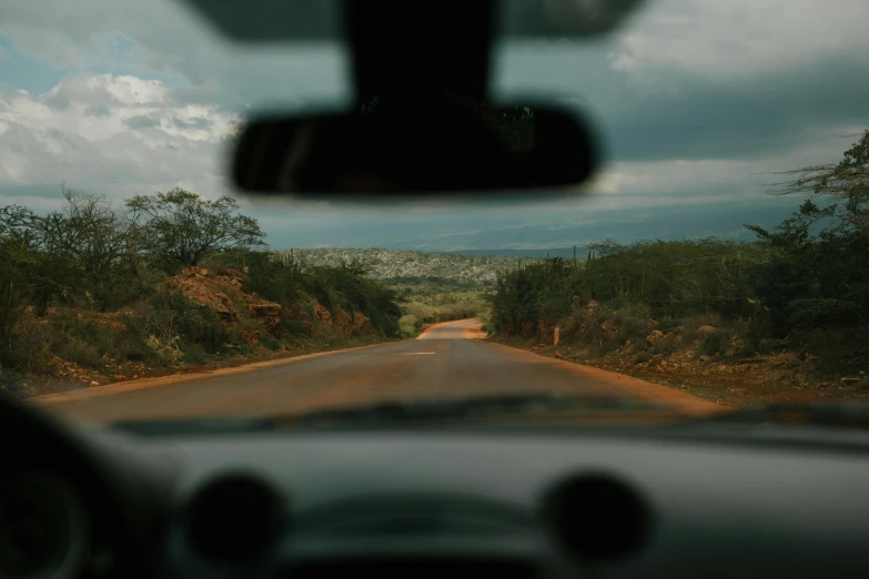 a view from inside a car looking at a dirt road and mountains