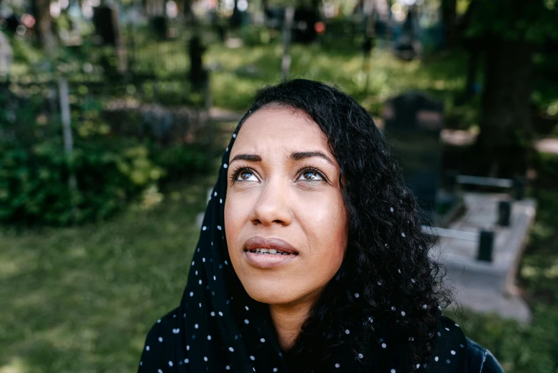 a close up of a person wearing a headscarf, by Julia Pishtar, in a graveyard, mixed-race woman, looking up, portrait image