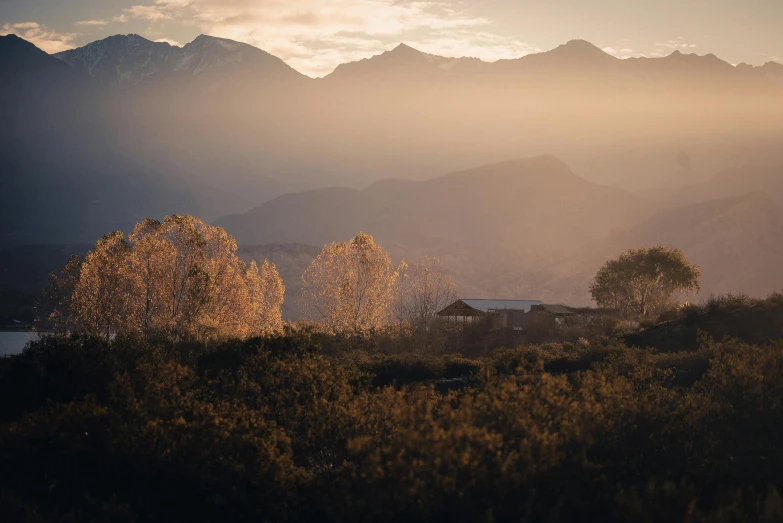 a house sitting on top of a lush green hillside, a picture, unsplash contest winner, australian tonalism, golden hour in beijing, distant mountain range, autumn foliage in the foreground, chile