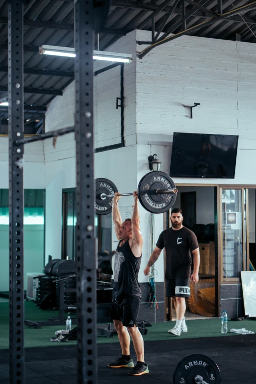 two men doing the overhead bar squat with a barbell