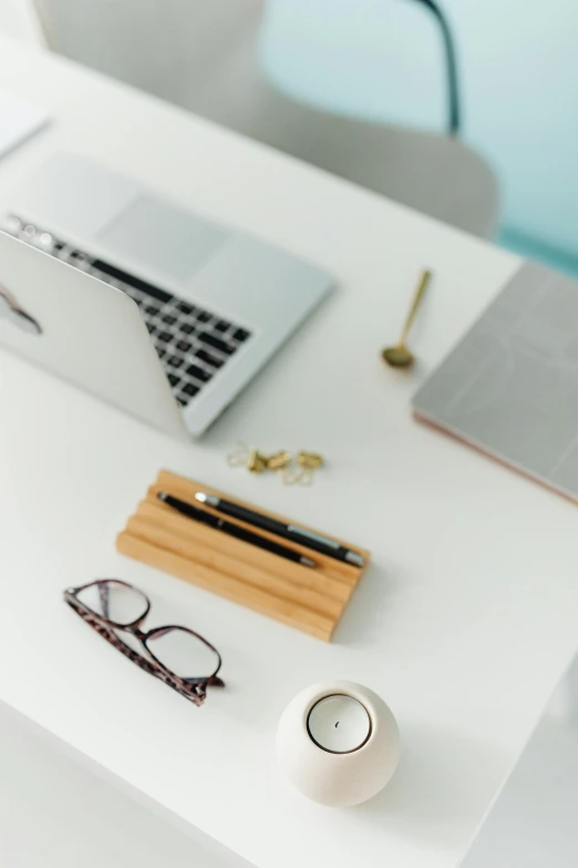 a laptop computer sitting on top of a white desk, trending on pexels, small square glasses, 1450