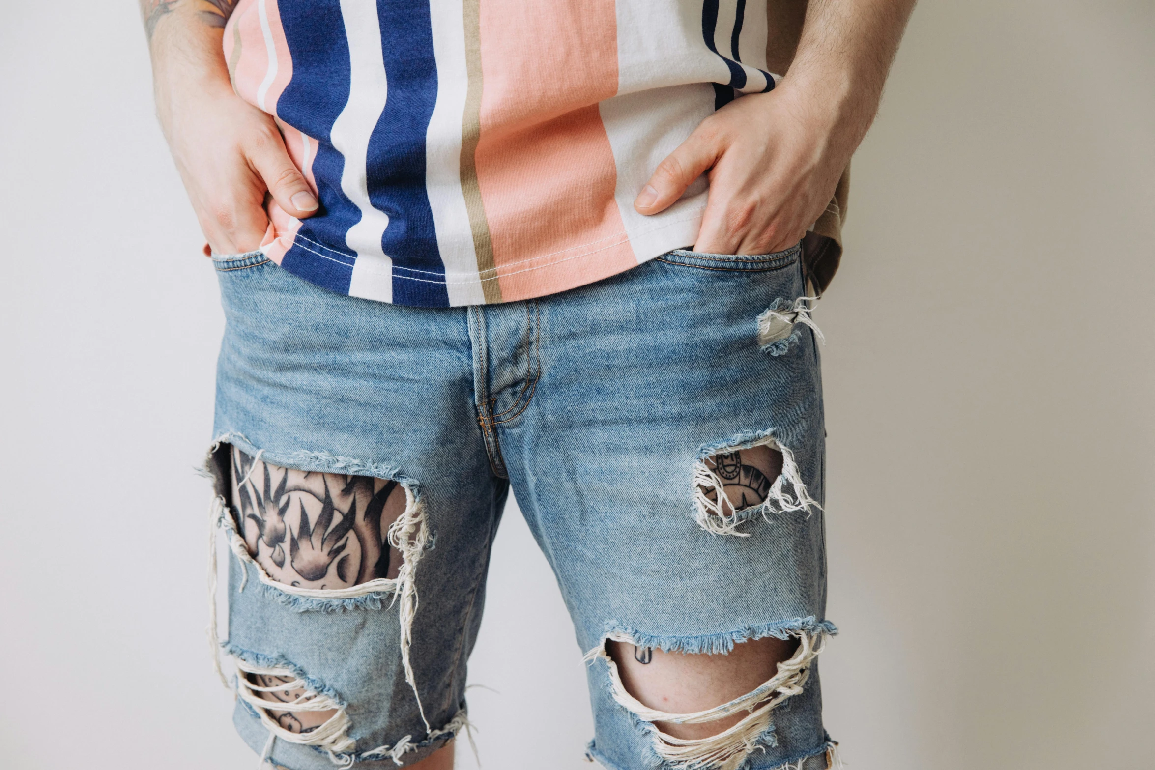 a man wearing ripped shorts with some tattoo