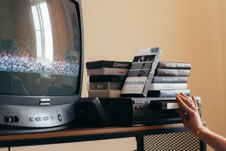 a person playing a video game on a television, inspired by Elsa Bleda, pexels contest winner, video art, stack of books on side table, expired film analog photography, black mirror series, vhs colour photography