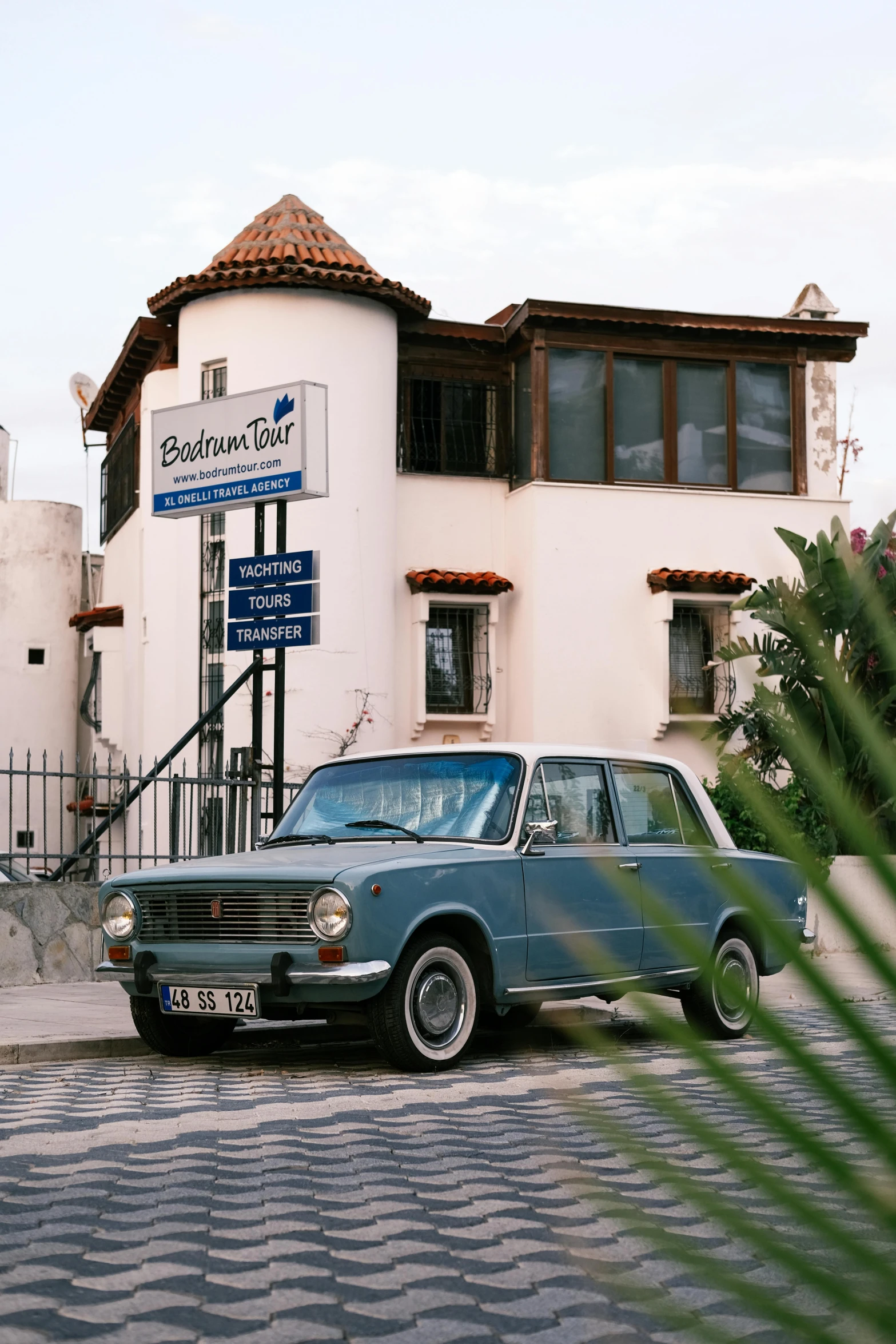 a blue car parked in front of a tall building