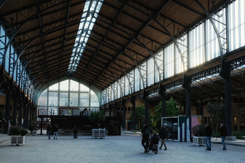 a couple of people that are standing in a building, a digital rendering, inspired by Pedro Álvarez Castelló, unsplash, train station in summer, some stalls, steel archways, panoramic