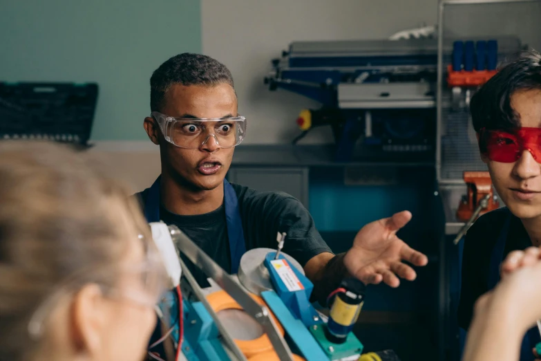 a couple of young men standing next to each other, pexels, academic art, handling laboratory equipment, tech glasses, darren bartley, in a classroom