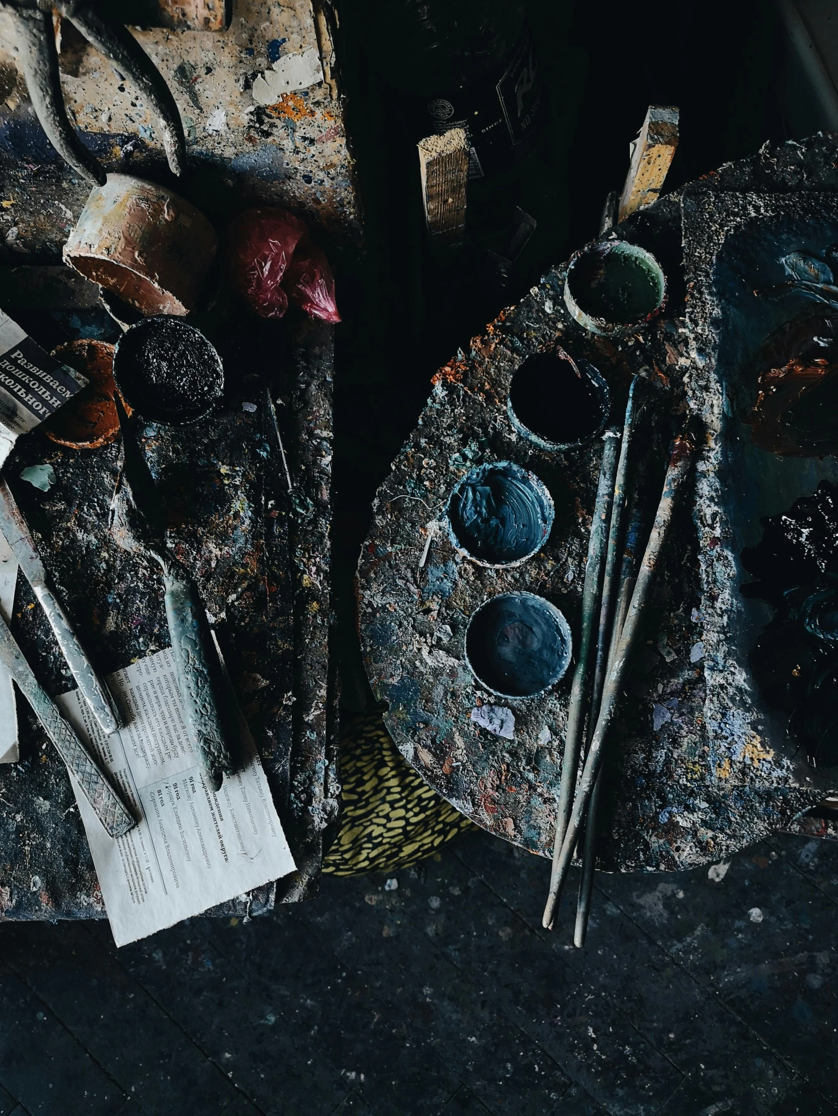 a pile of paint brushes sitting on top of a table, a still life, inspired by Pollock, trending on unsplash, dark colour palette, tools and junk on the ground, volcanic workshop background, instagram story