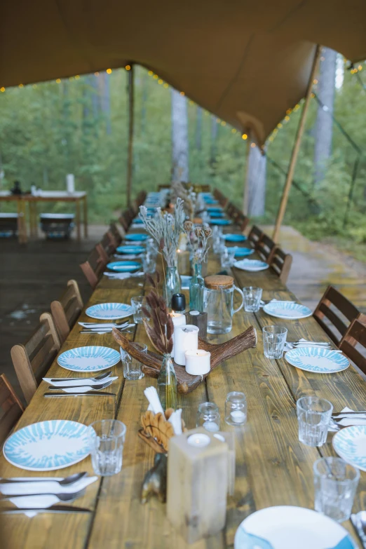 a long wooden table topped with plates and glasses, glamping, woodlands, canopies, uk