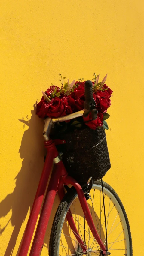 a bike is leaning against a yellow wall with a basket on it