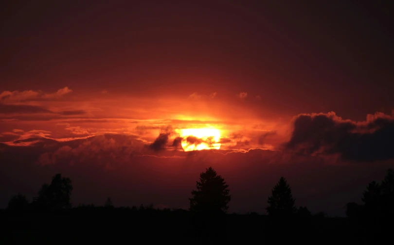 the sun is setting behind the clouds in the sky, a picture, forest fires in the distance, golden hour photograph, glowing red, silhouetted