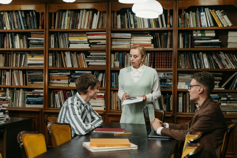 a group of people sitting around a table in a library, lachlan bailey, retro vibe, yulia nevskaya, academic clothing