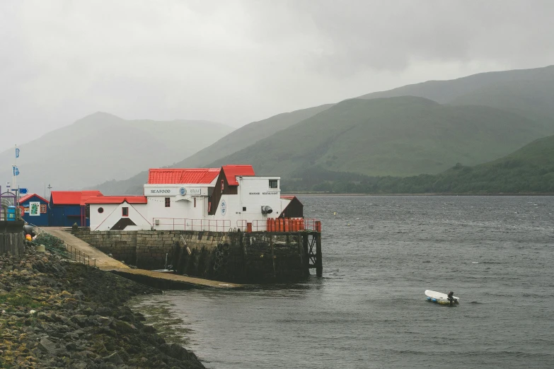 a boat sitting on top of a body of water, a photo, white buildings with red roofs, highlands, atmospheric photograph, near a jetty