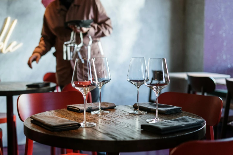 a couple of wine glasses sitting on top of a wooden table, pexels contest winner, renaissance, chef table, urban setting, standing upright, group sit at table