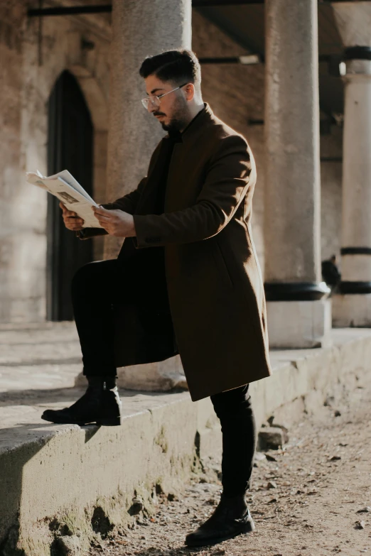 a man sitting on a ledge reading a book, pexels contest winner, romanticism, brown tuffle coat, standing elegant pose, charts, on the ground