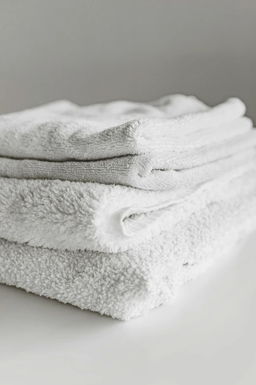 a stack of white towels sitting on top of a table, thumbnail, overdetailed, grey, a small