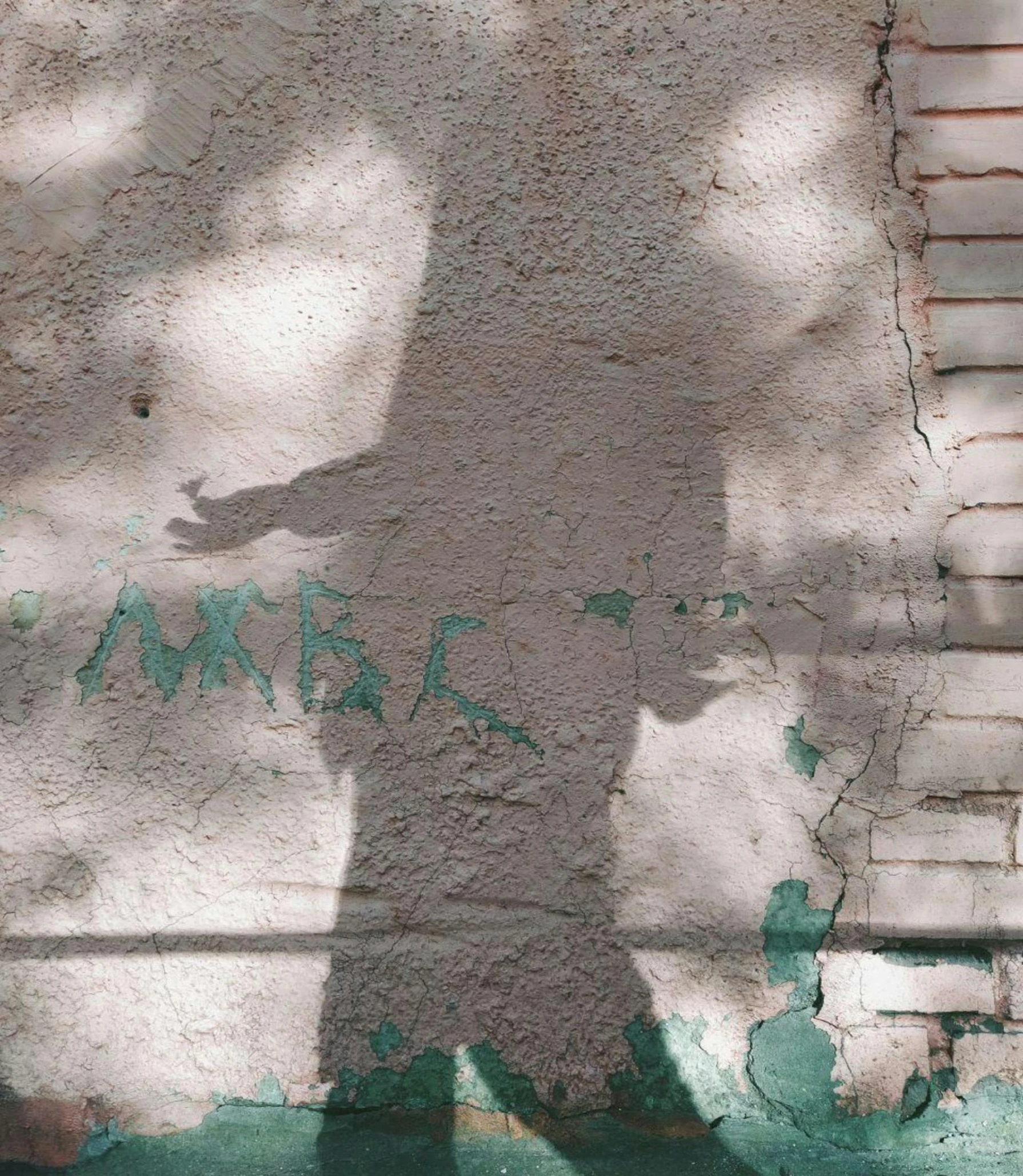 a shadow of a person on the side of a building, by Pablo Rey, unsplash, graffiti, with damaged rusty arms, color image, a labeled, ambeint