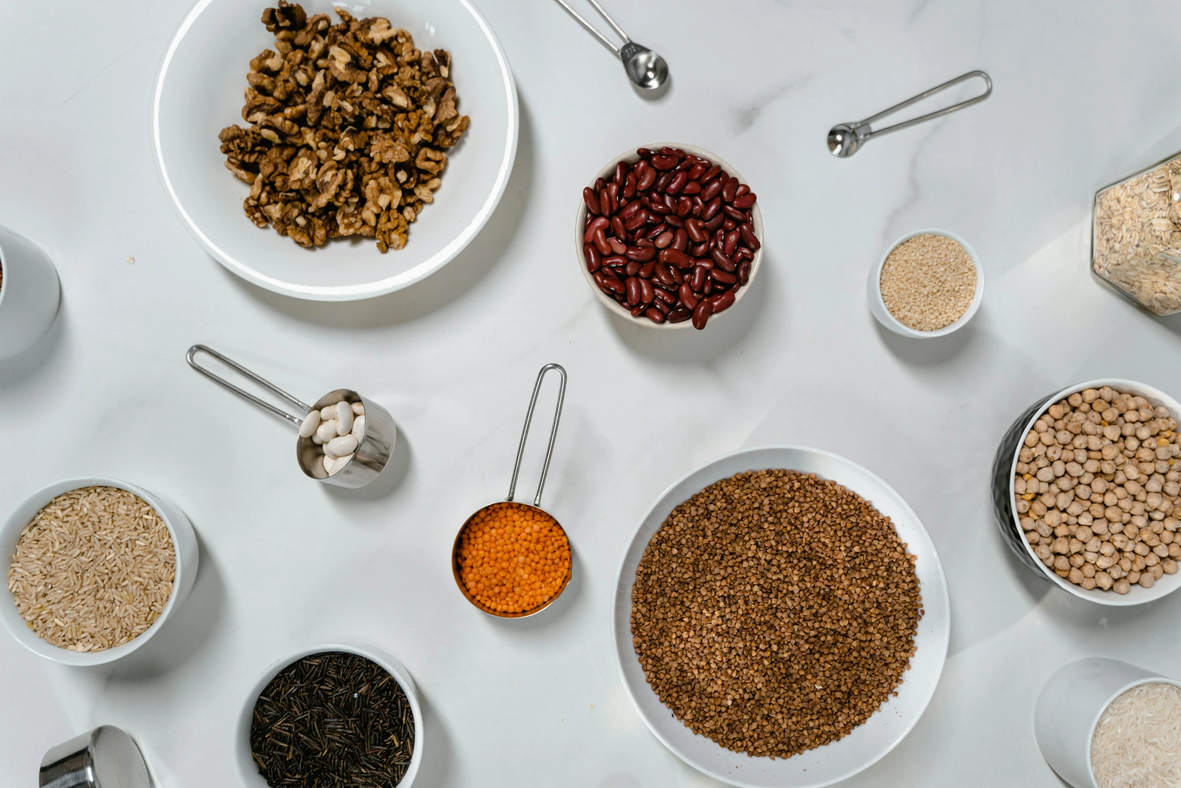 a table topped with bowls filled with different types of food, by Carey Morris, trending on pexels, mineral grains, on grey background, beans, background image