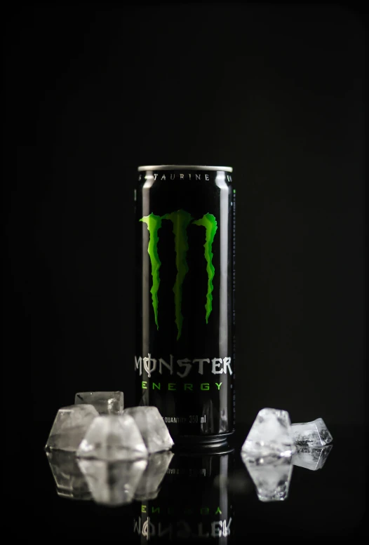 a monster energy drink with ice chunks in the foreground