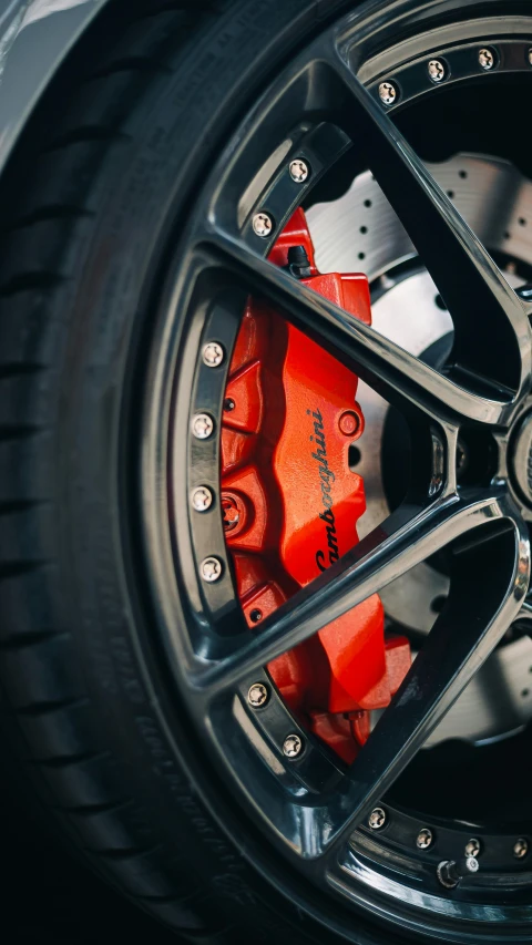 a close up of a red brake on a car, unsplash, instagram picture, ap news photo, colorized, wheel