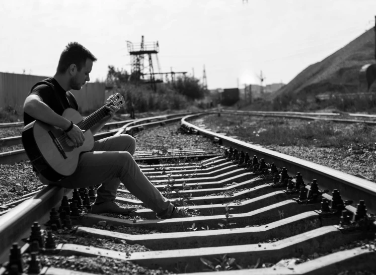 a person with a guitar on some railroad tracks