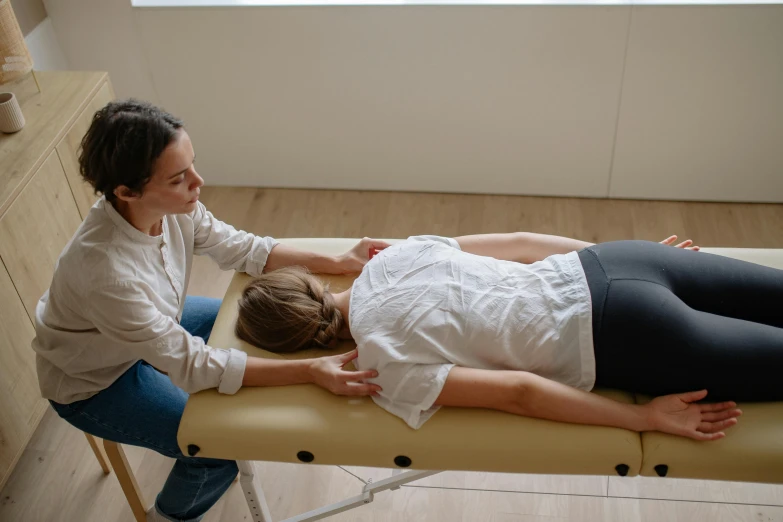 a woman getting a massage in a room, on a table, lachlan bailey, medical reference, on a white table