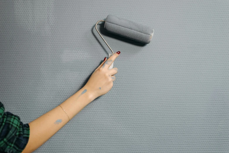 someone using a paint roller to fix the grey paint