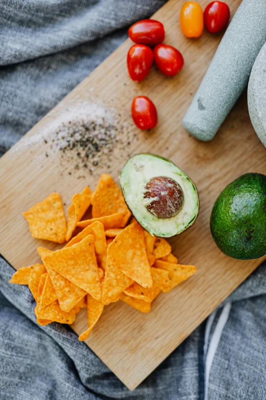 a wooden cutting board topped with tortillas and guacamole, a still life, trending on pexels, process art, crisps, avacado chairs, grey, a small