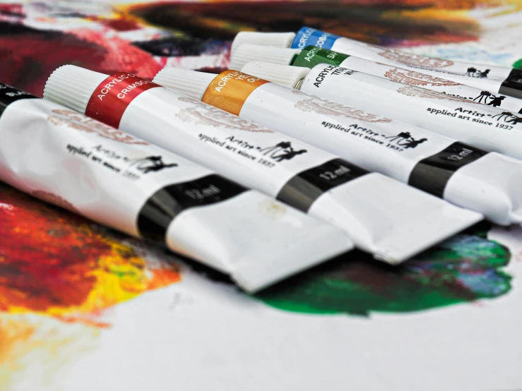 four tubes of art paint sitting on a table