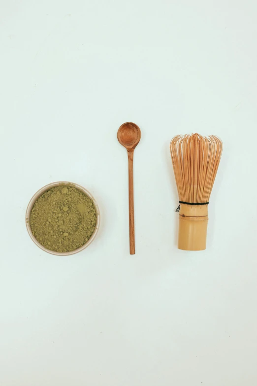 a whisk next to a bowl of matcha and a wooden spoon, dau-al-set, detailed product image, various items, light tan, slightly pixelated