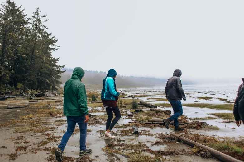 a group of people walking across a muddy beach, by Jessie Algie, unsplash, land art, british columbia, background image, hiking clothes, floating in a misty daze