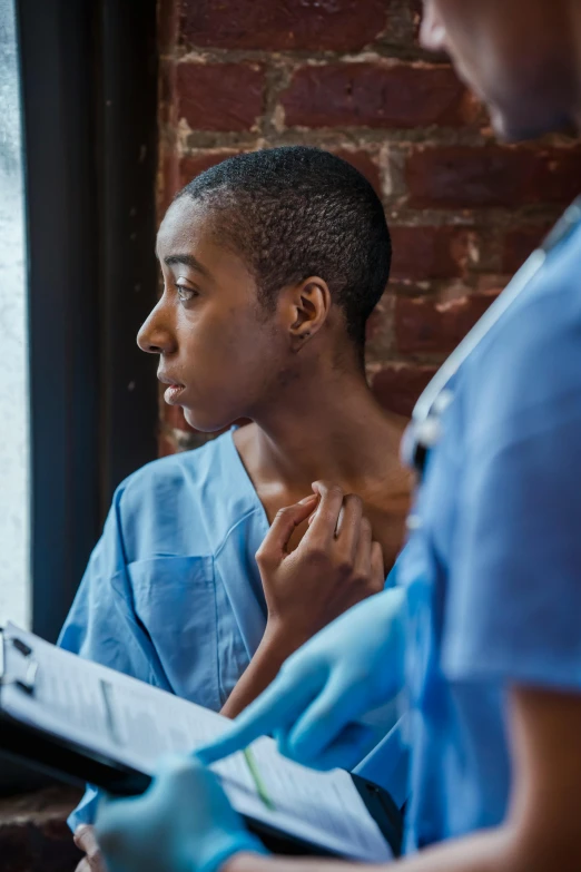 a man and woman in scrubs looking out a window, a photo, trending on pexels, happening, black teenage boy, at the hospital in patient gown, lesbians, studying