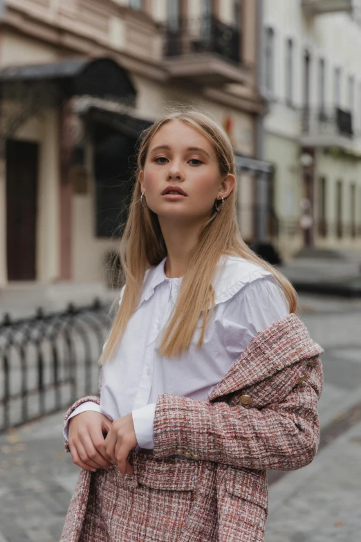 a woman standing in the middle of a street, by Emma Andijewska, trending on pexels, wearing a white button up shirt, thick collar, olya bossak, during autumn