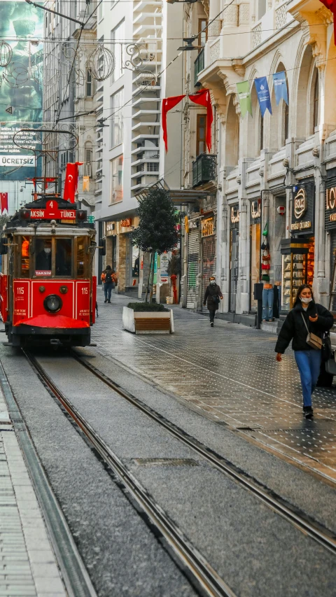 a cable car on a city street with people walking