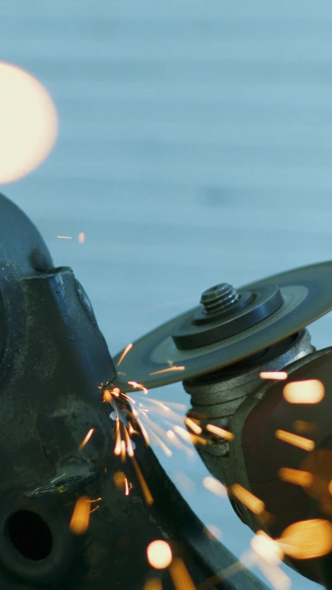 a person grinding metal with a grinder, an album cover, by David Simpson, pexels contest winner, mechanical parts, photographed for reuters, animation, close establishing shot