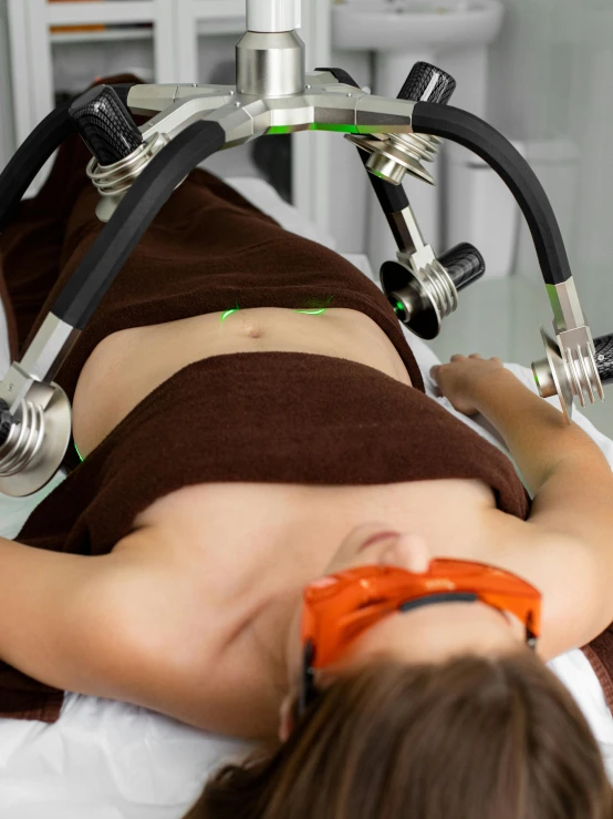 a woman laying on top of a bed next to a machine, body fitted dart manipulation, medical lighting, avatar image, sports photo