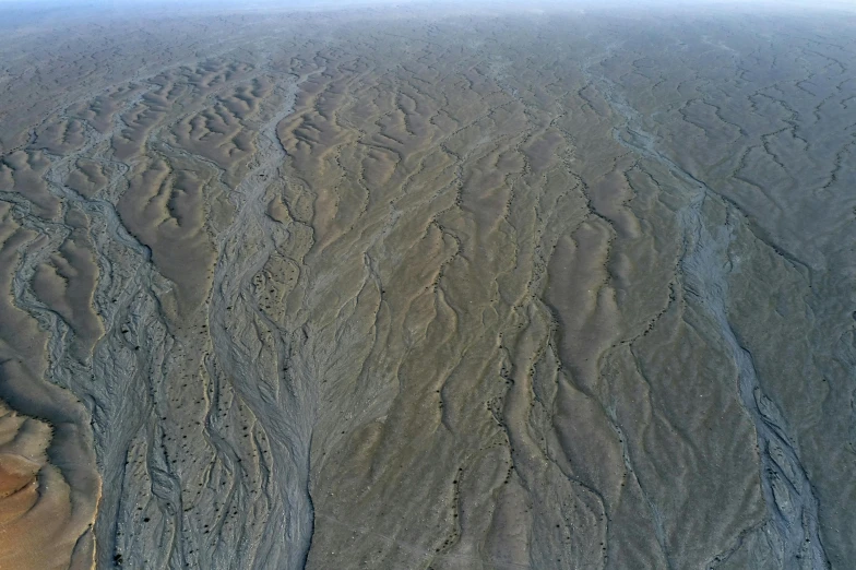 an aerial view of some sand and water, hurufiyya, flowing lines, tectonic sky, modeled, brown stubble