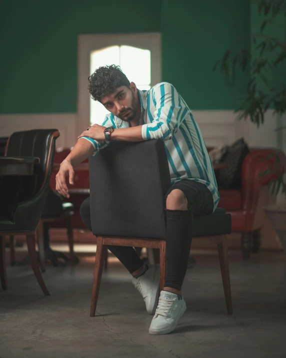 a man sitting on top of a wooden chair in front of a table