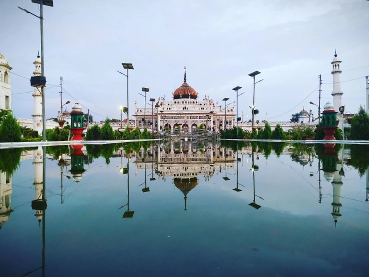 a reflection of a building in a pool of water, by Basuki Abdullah, pexels contest winner, art nouveau temple, outdoor fairgrounds, downtown mexico, parks and public space