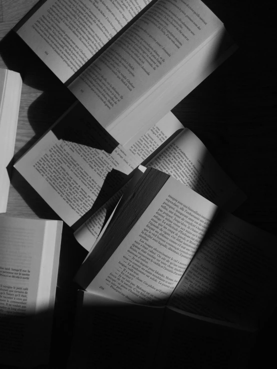 a pile of books sitting on top of a table, a black and white photo, by Karl Buesgen, unsplash contest winner, lights and shadows, cinematic. by leng jun, dark university aesthetic, jovana rikalo