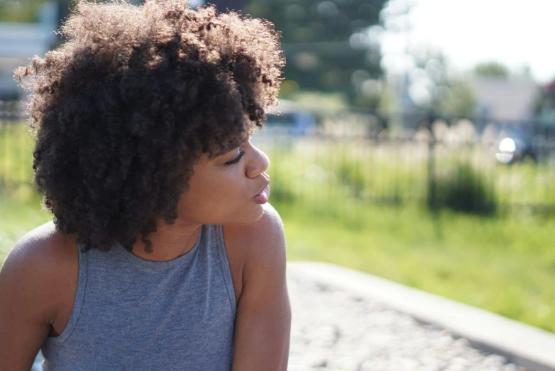 a close up of a person with a skateboard, by Alice Mason, pexels contest winner, happening, natural hair, contemplating, at a park, looking her shoulder