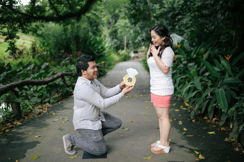 a man kneeling down next to a woman holding a donut, by Basuki Abdullah, pexels contest winner, botanic garden, pregnant, holding gift, avatar image