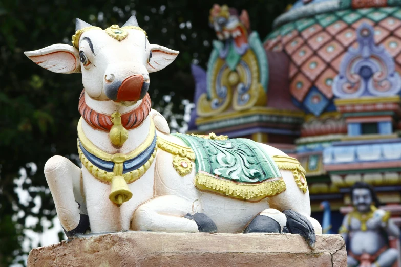 a statue of a cow sitting on top of a rock, a statue, unsplash, sumatraism, colourful biomorphic temple, kalighat highly detailed, square, deity)