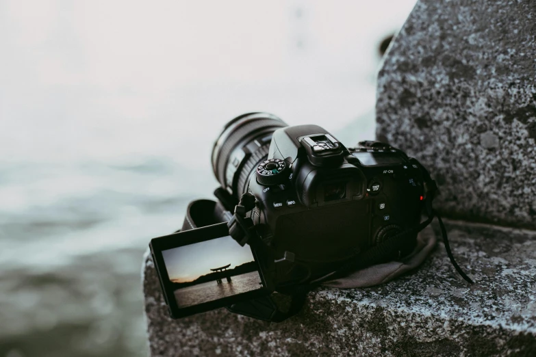 a camera sitting on top of a rock next to a body of water, a picture, back to camera, ecommerce photograph, clean image, medium-shot