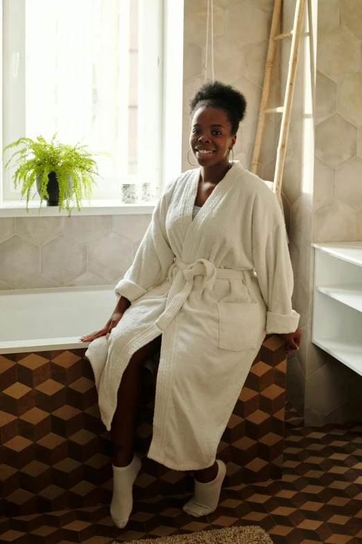 a woman sits on the edge of her bathtub and smiles