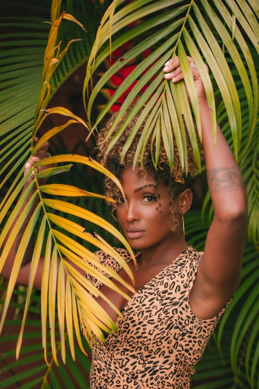 a woman standing in front of a palm tree, a portrait, trending on pexels, renaissance, ashteroth, big leaf bra, with textured hair and skin, vines