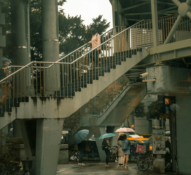 a couple with umbrellas walk up steps near bikes